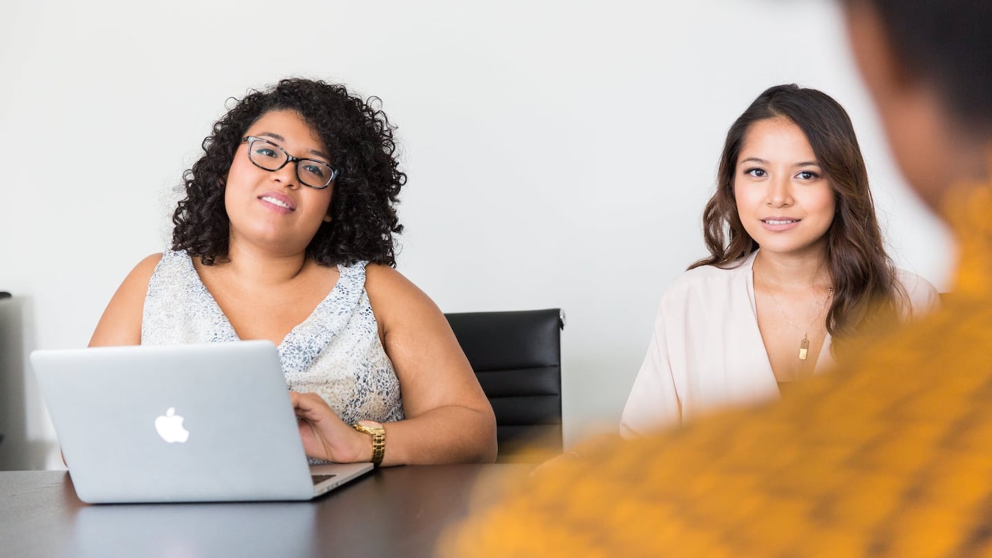 Two recruiters sit at a table while interviewing a candidate