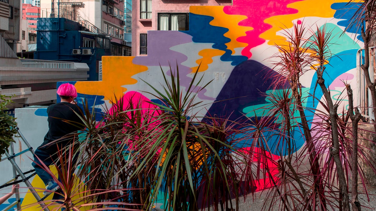 Local artist Zoei Lam paints a mural onto a wall in the Sheung Wan district of Hong Kong.