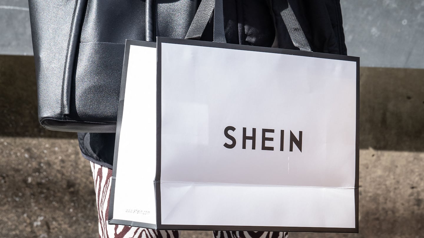 A shopper carries a white Shein shopping bag.