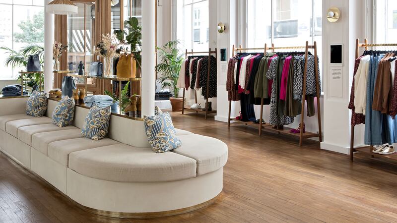 Sézane store interior with a large seating area and racks of clothing.