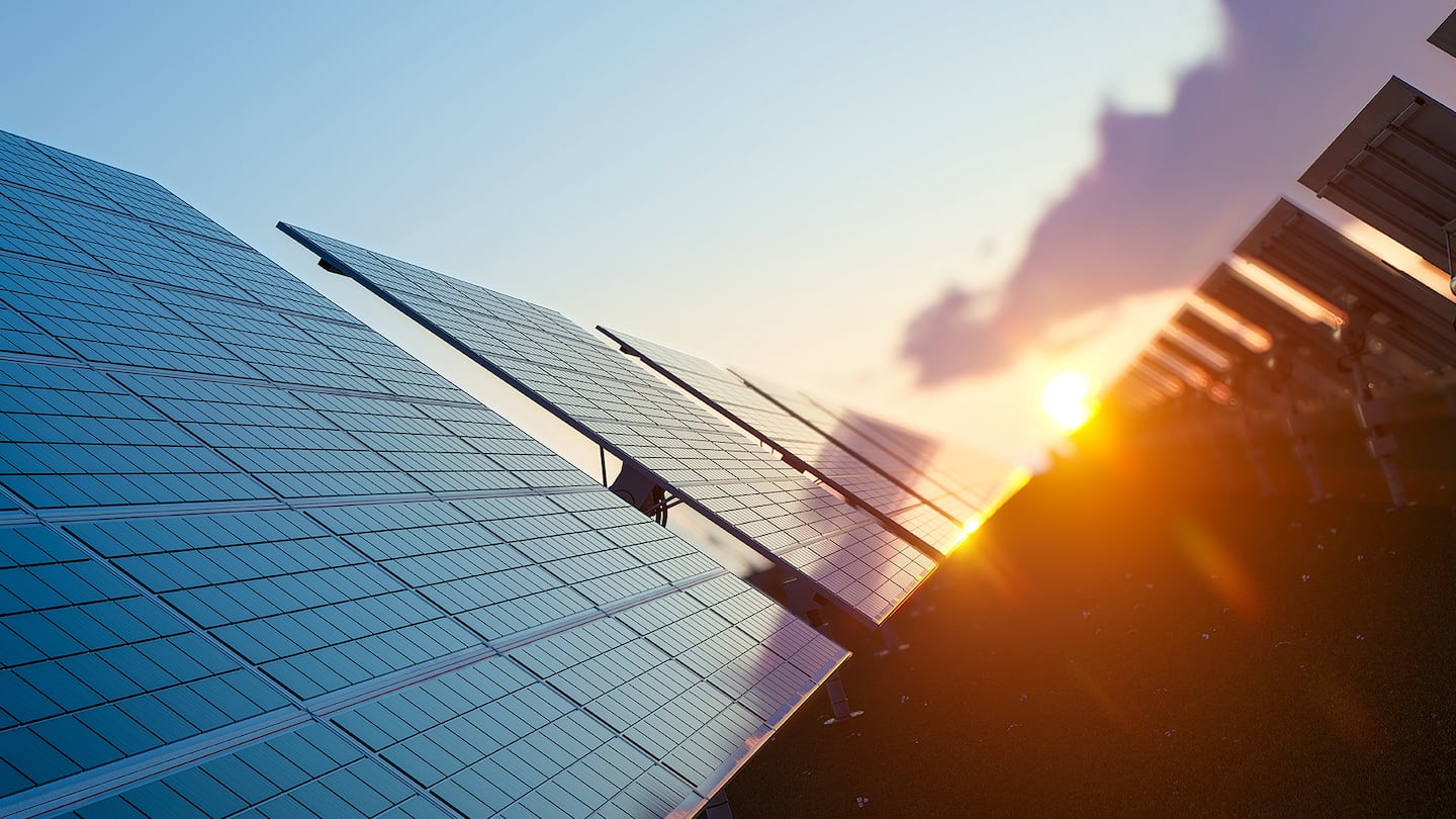 The sun sets over a field of solar panels.