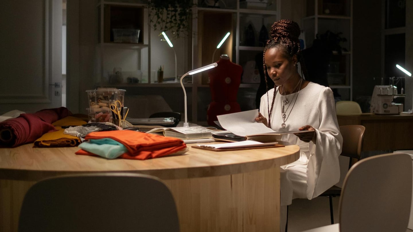 A creative in the fashion industry sits at a desk looking through some papers.